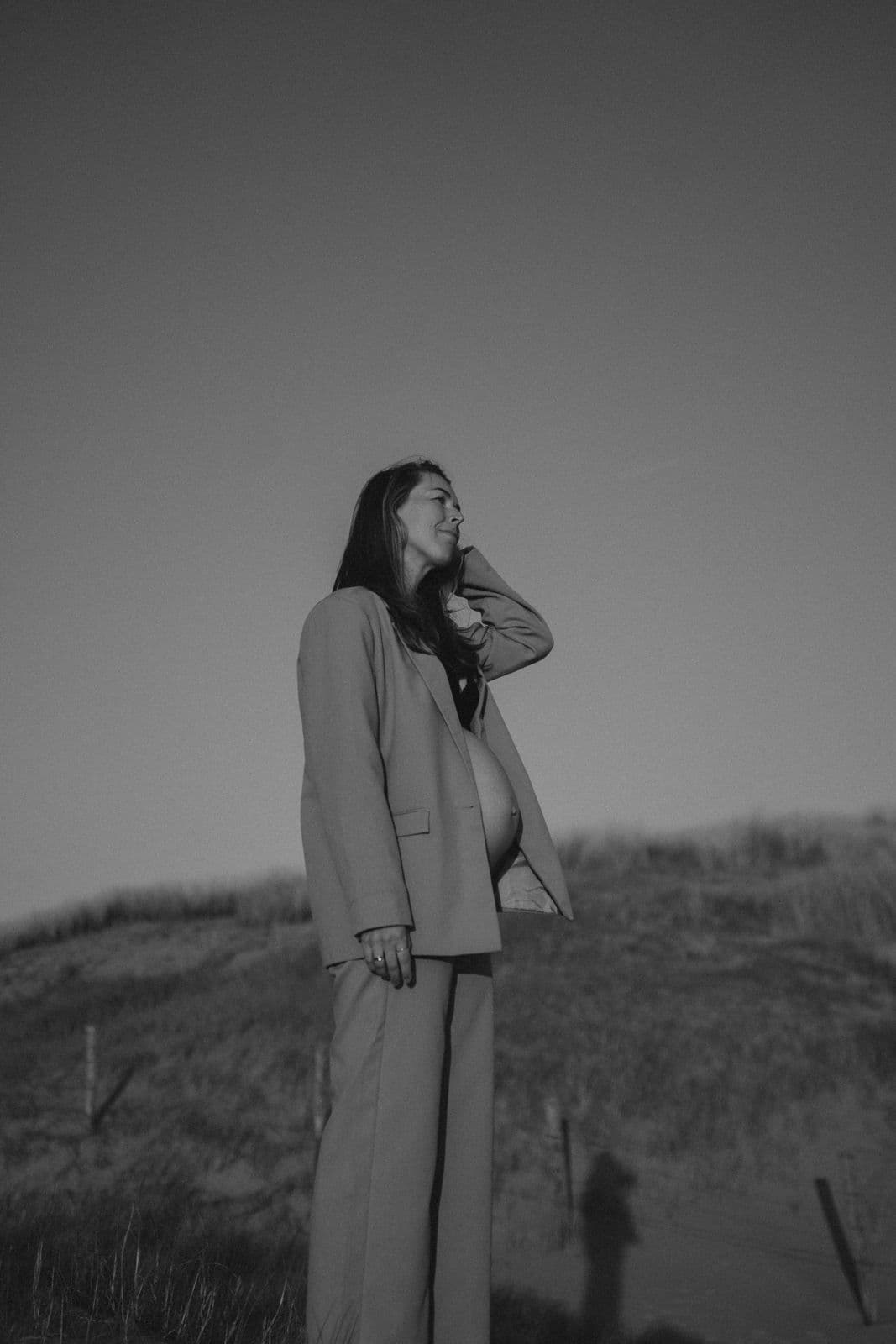 Manon de Jong staat in de duinen aan zee, bij laag licht.