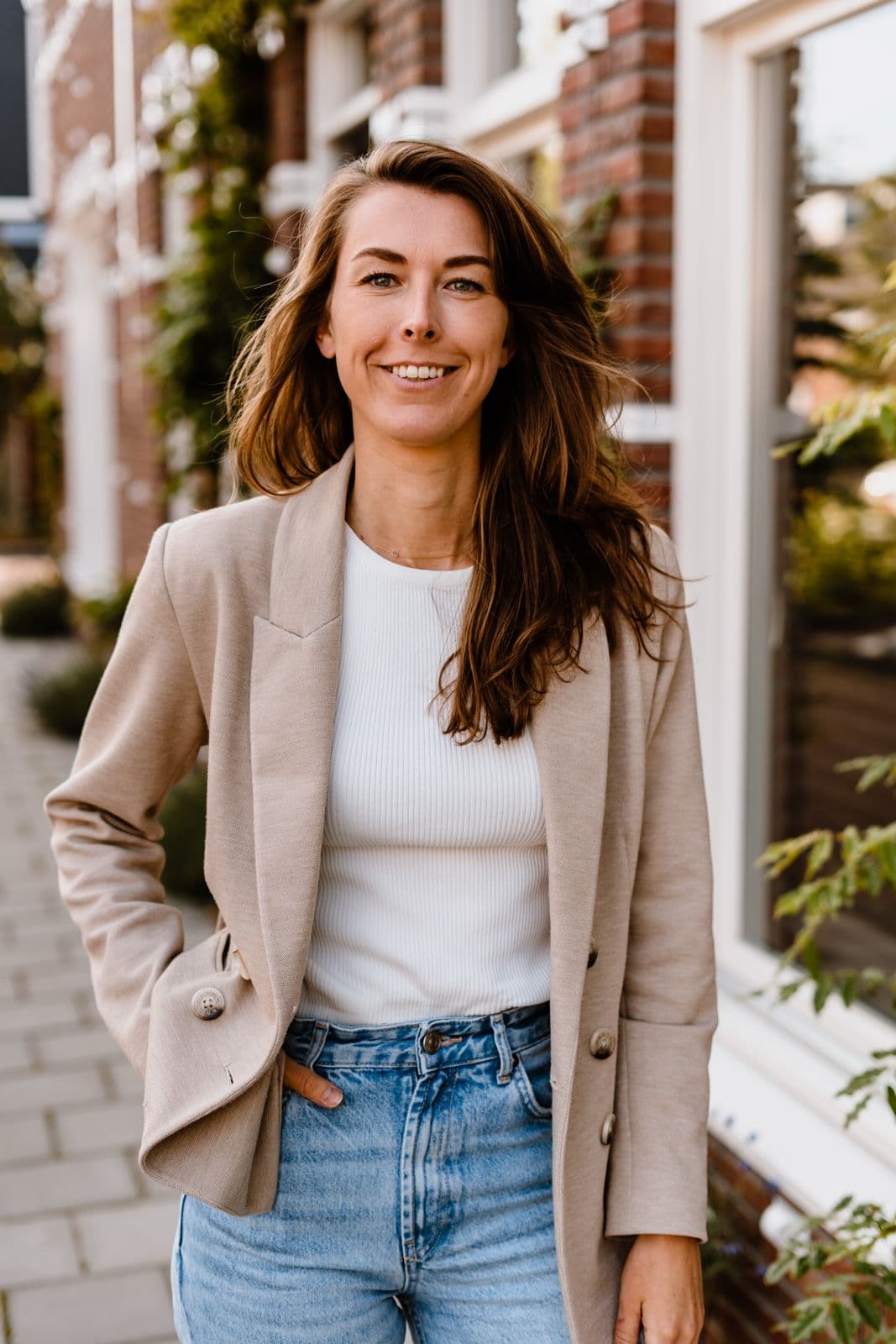Manon de Jong, staand voor een woonhuis.
